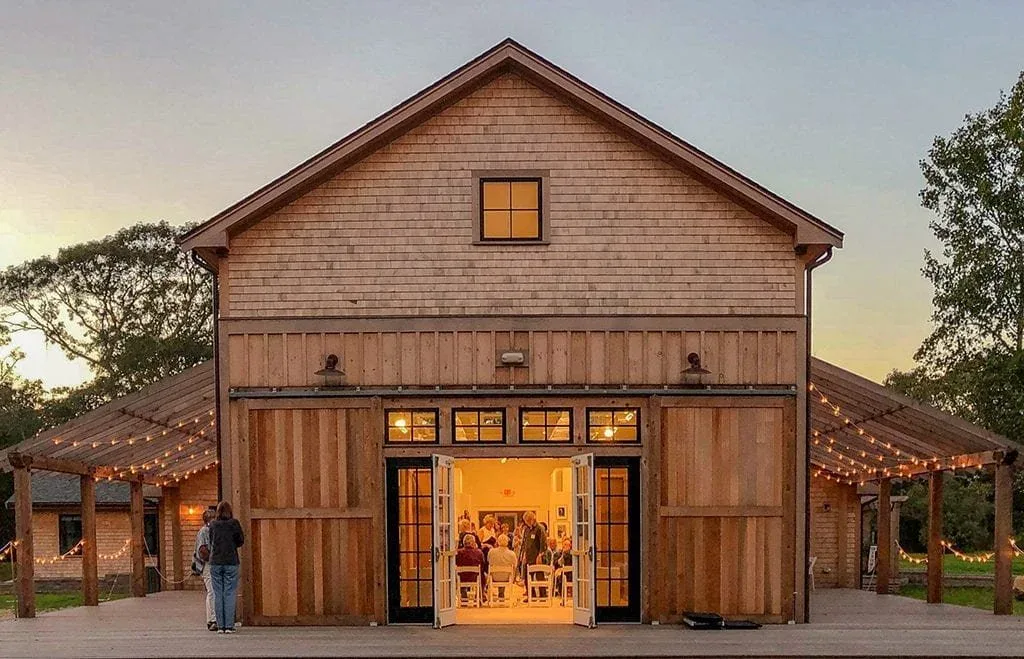 Featherstone barn at dusk with string lights and an indoor gathering